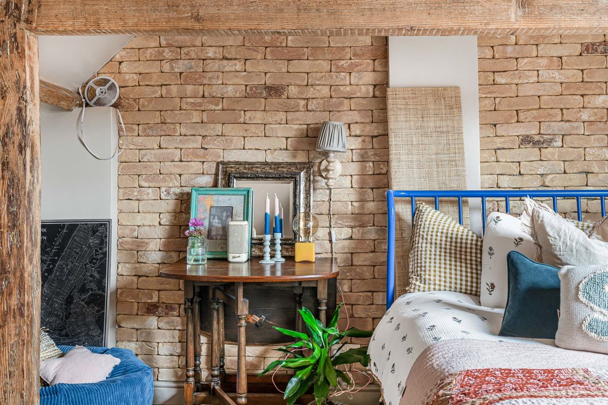 Exposed brick and a timber post beside the bed in the second-floor bedroom