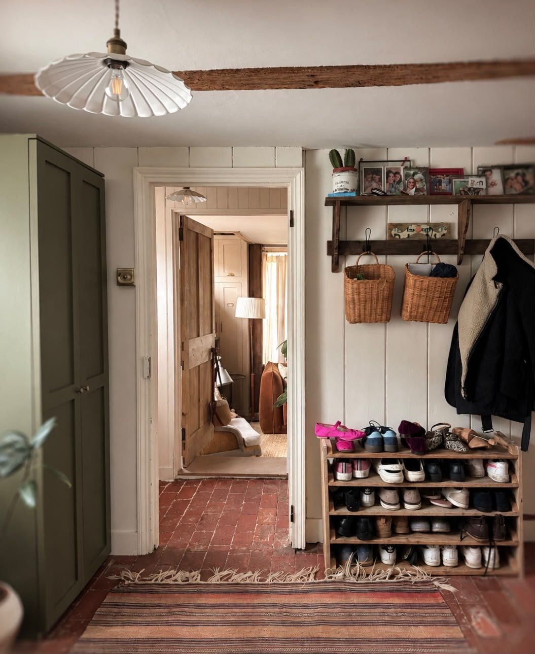 Coats, boots and shelves by a doorway, with a brick floor