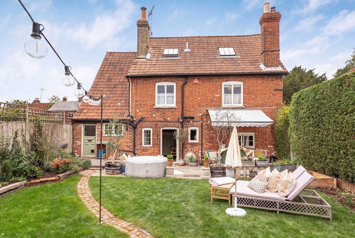 The rear of the house from the lawn, the paved terrace set with chairs