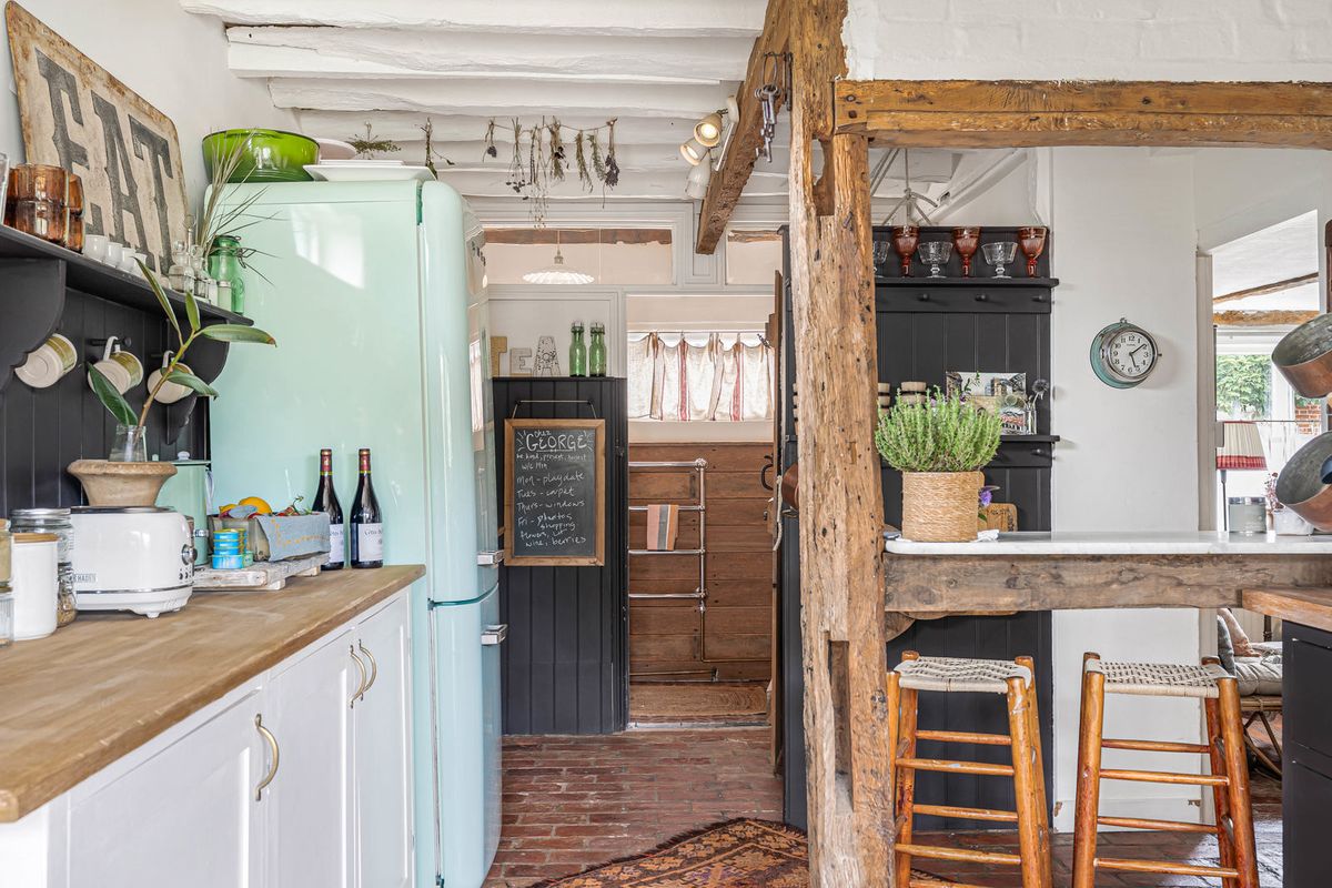 The kitchen bar with stools, set within the timber frame, a pale green fridge beside it